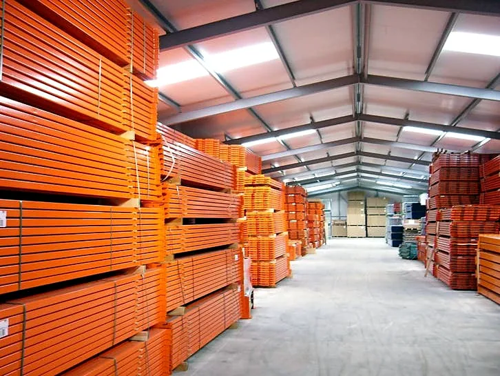 Gang door de loods van Roscom tussen stapels oranje liggers