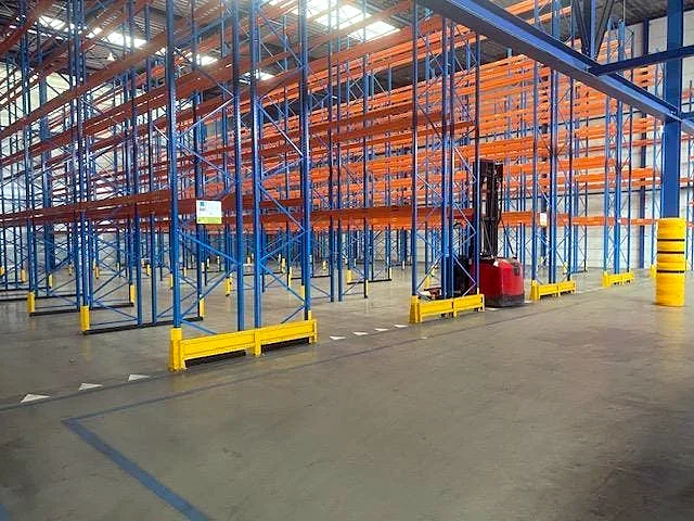Een magazijn met blauwe palletstellingen en oranje liggers